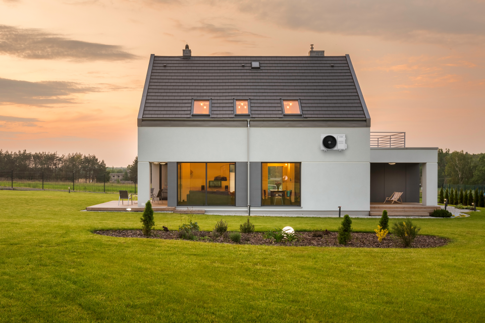 Neubau mit einer Terrasse und umgeben von viel Grünfläche, an der Außenfassade die Bosch Climate 3000i Außeneinheit